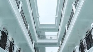 Un immeuble à plusieurs étages doté de balcons, de garde-corps et d’un escalier central.