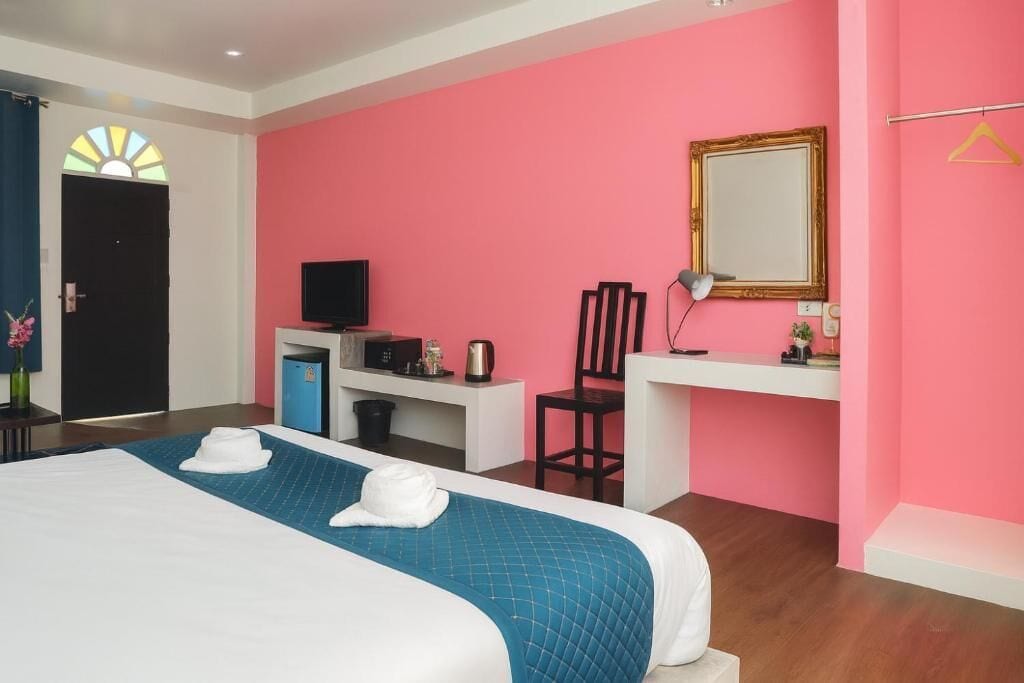 A hotel room with a bed, a desk, a chair, a television, and a mirror.