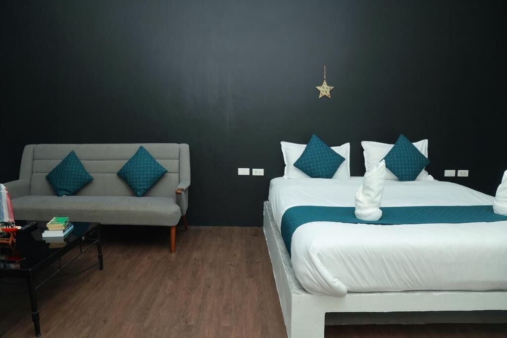 A hotel room with a bed, a sofa, a coffee table, and a wall-mounted star decoration.