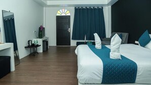 Une chambre d’hôtel avec un lit, un bureau, une chaise, un miroir, une porte et une fenêtre avec des rideaux.