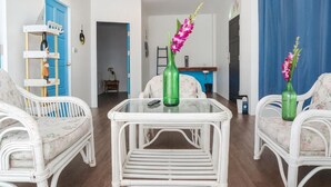 Un salon avec des meubles en osier, une table basse en verre et deux vases ornés de fleurs.