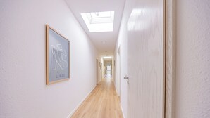 A narrow hallway with wooden flooring, a skylight, and a framed artwork on the wall. - Hillerts Hotel (Rheda-Wiedenbrück)