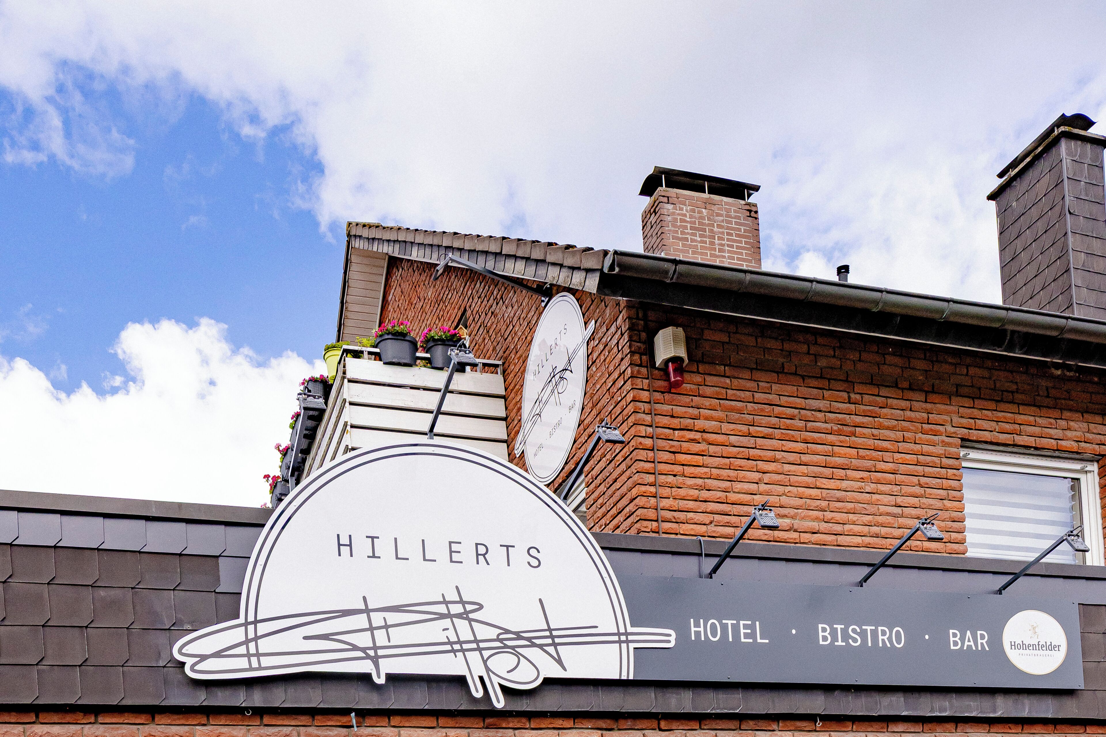 Un bâtiment sur lequel on peut lire l’inscription « HILLERTS HOTEL BISTRO BAR » et qui arbore le logo de « Hohenfelder ».