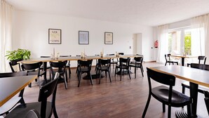 A dining area with multiple tables and chairs, framed artwork on the walls, and a potted plant. - Hillerts Hotel (Rheda-Wiedenbrück)