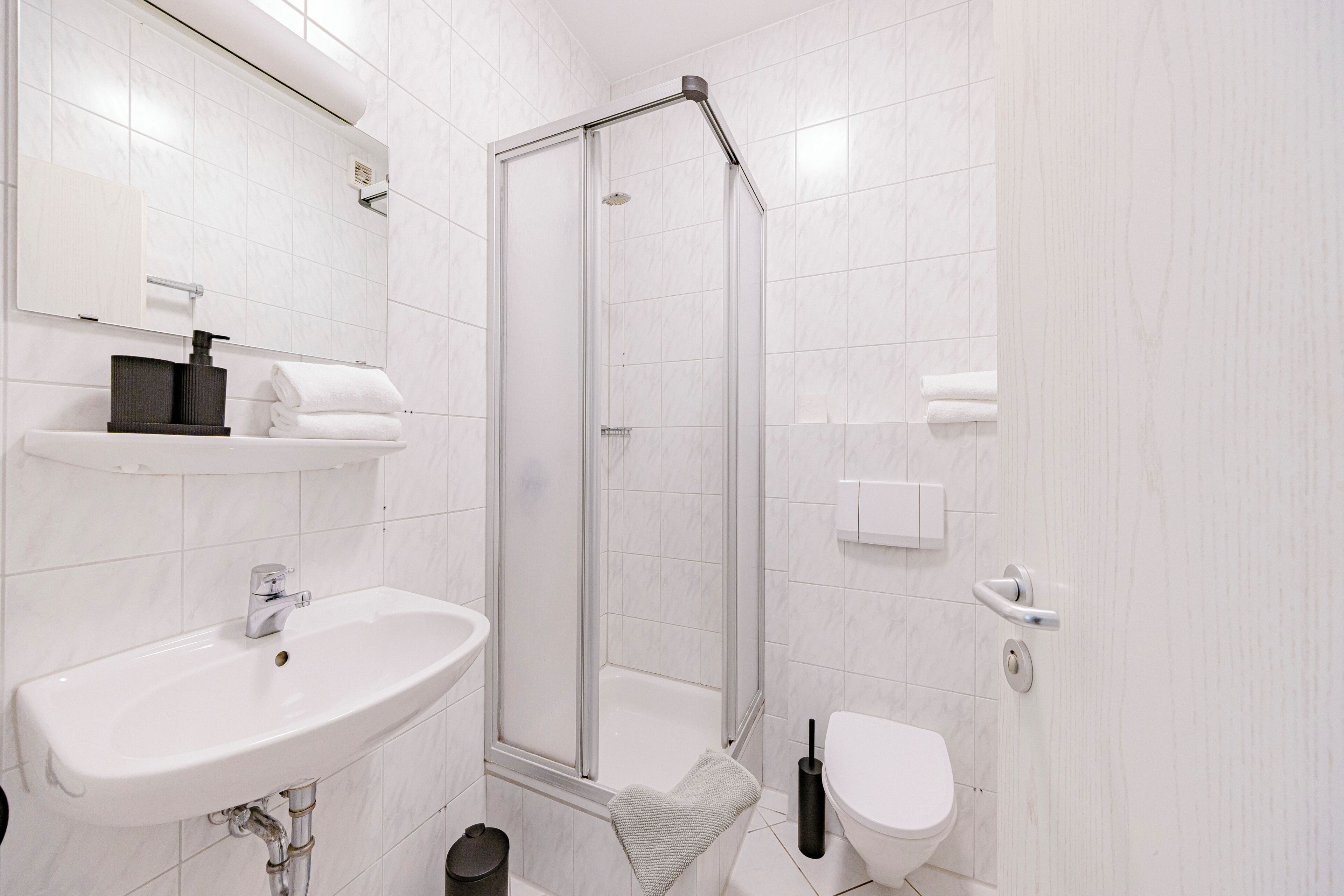 A modern bathroom with a white sink, toilet, and shower.