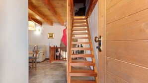 Un escalier en bois mène à une mezzanine où se trouvent une chaise rouge et une table.