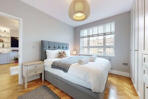 Un dormitorio con una cama grande, mesitas de noche, una ventana y un armario empotrado.