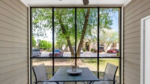 A covered patio with a table and chairs, a view of a parking lot and trees, and a building in the background. - Travel Ball-Travel Nurses-OWA-9.7 miles To Beach (Foley)