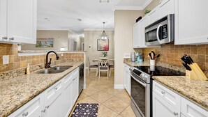 A kitchen with granite countertops, white cabinets, a microwave, and a dining area with a table and chairs. - Travel Ball-Travel Nurses-OWA-9.7 miles To Beach (Foley)