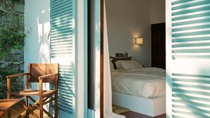 Une porte ouverte donne sur une chambre à coucher qui contient un lit, une table de chevet et une chaise.