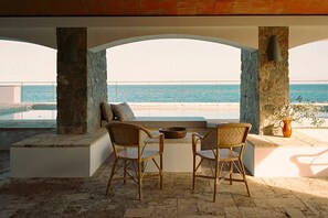 A terrace with two wicker chairs, a stone wall, and a view of the sea. - Villa Estasia front sea - My Rental Homes (Begur)