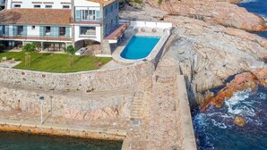 Une propriété située sur la côte, dotée d’une piscine, de murs en pierre et offrant une vue sur la mer.