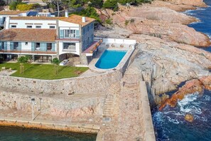 Ein Küstenanwesen mit Pool, Steinmauern und Meerblick.