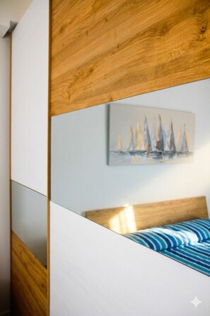 A bedroom with a bed, a painting, and a wooden headboard. - Affittimoderni Castelsardo - North West Apt (Castelsardo)