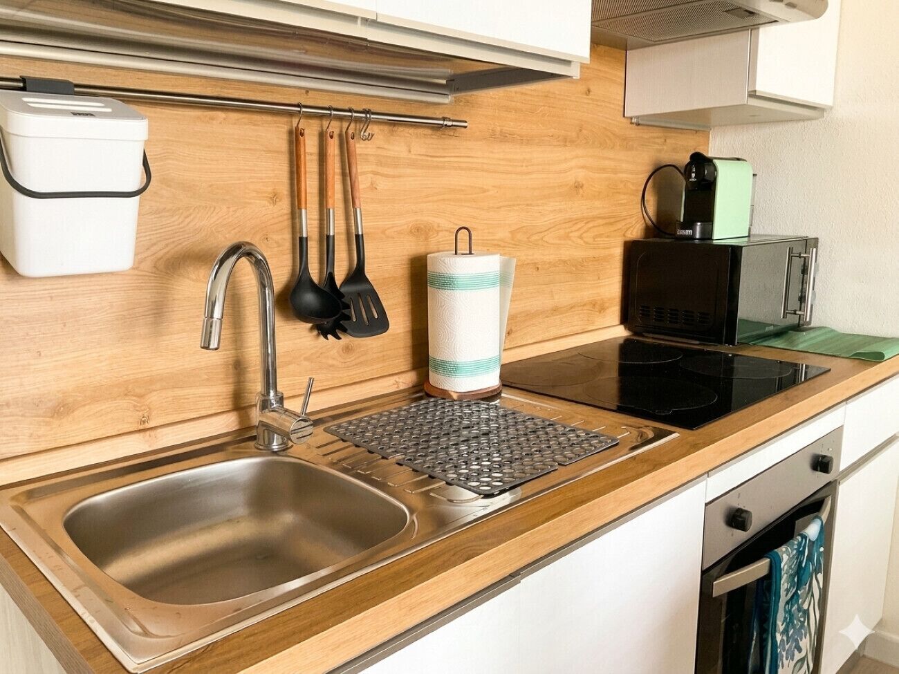 A kitchen with a sink, stove, and various utensils.