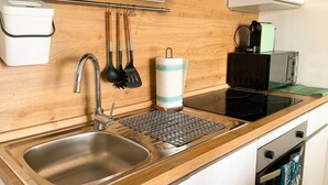 Una cocina con un lavamanos, estufa y diversos utensilios.