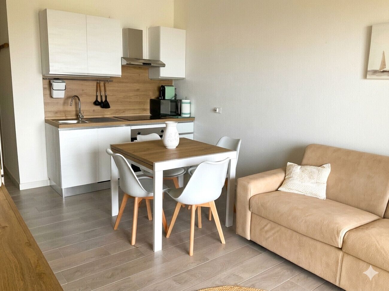 A compact living space with a kitchenette, a dining table with chairs, and a sofa.