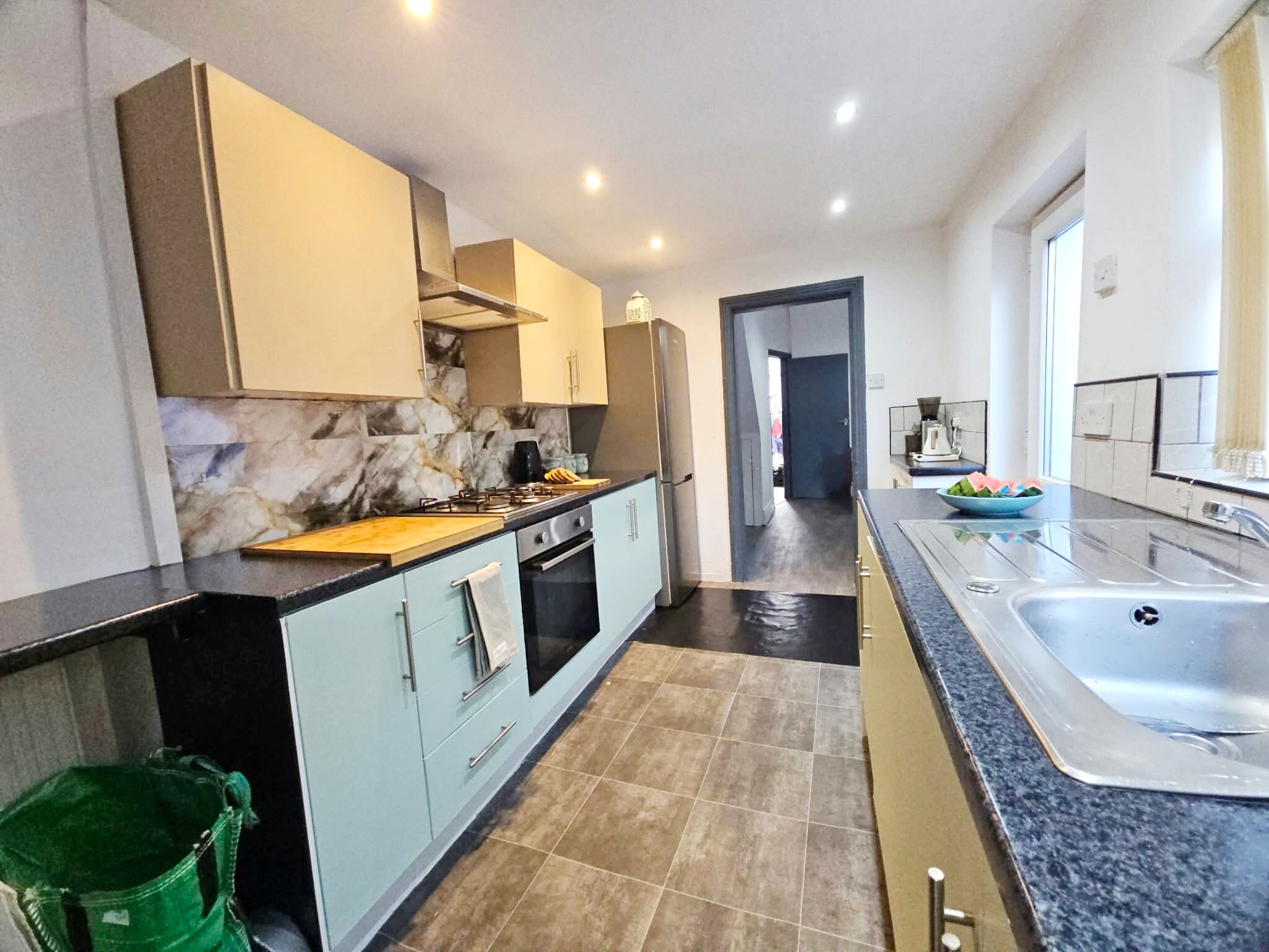 A modern kitchen with marble backsplash, stainless steel appliances, and a large sink.