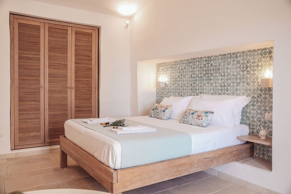 Une chambre à coucher avec un lit en bois, une table de chevet, une tête de lit à motifs et une armoire.