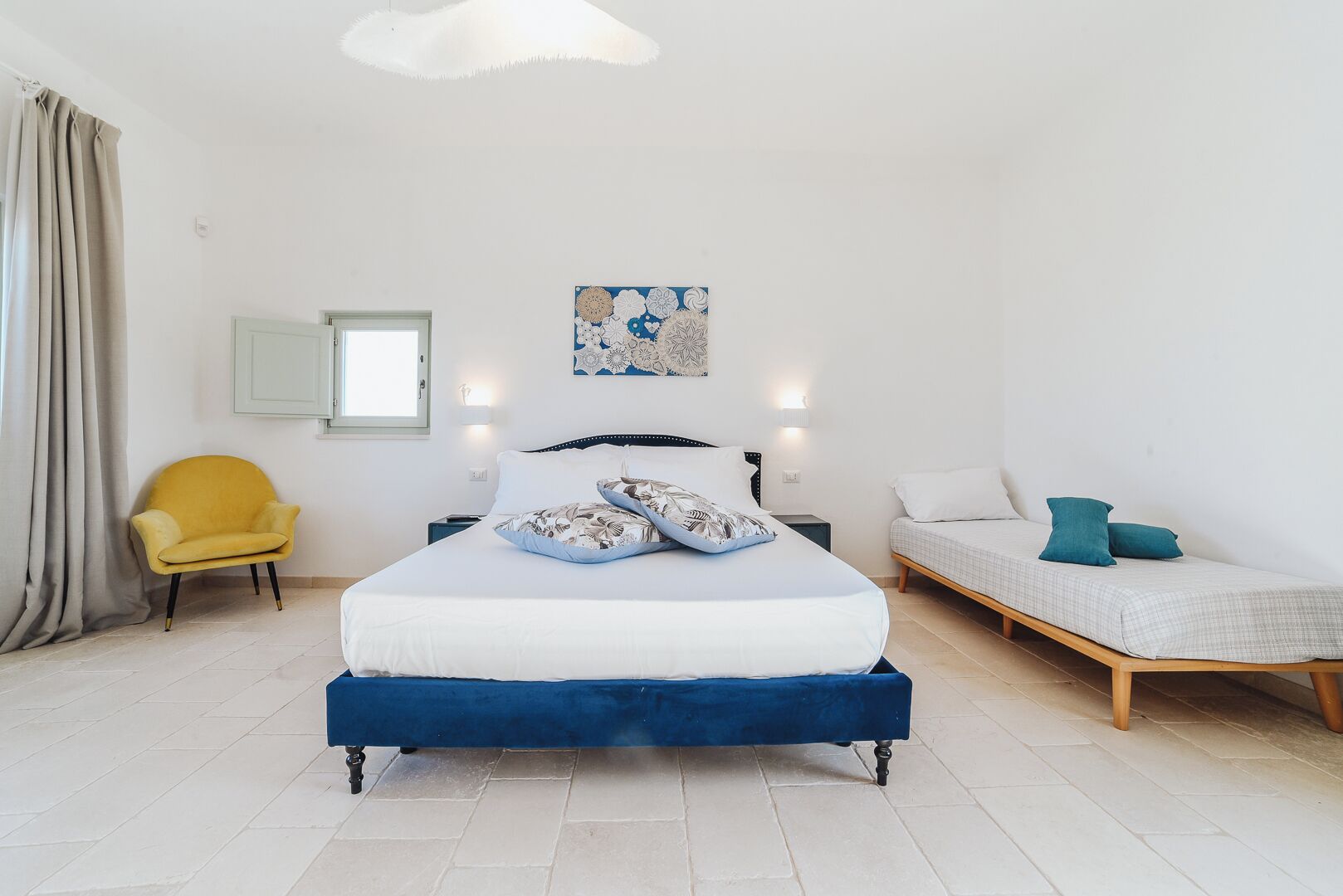 Een slaapkamer met een bed, een stoel, een bank en een kunstwerk aan de muur.