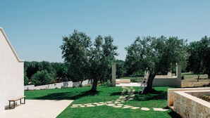 A courtyard with a paved walkway, a bench, and a stone wall. - DIMORA STUNE (Ostuni)