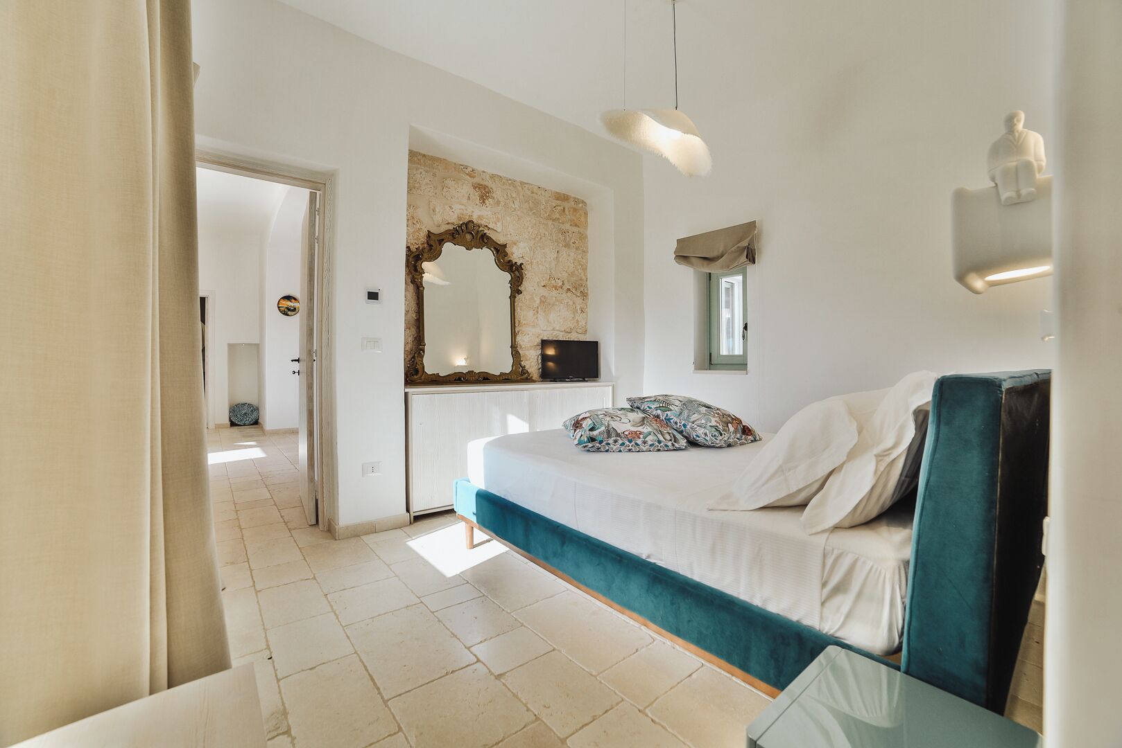 Une chambre à coucher comprenant un lit, une commode, un miroir et un luminaire suspendu.