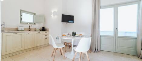 Cozinha moderna com área de refeições, televisão de tela plana e vista através de uma grande janela.
