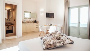 A hotel room with a bed, a desk, a television, and a view of the sea. - DIMORA STUNE (Ostuni)