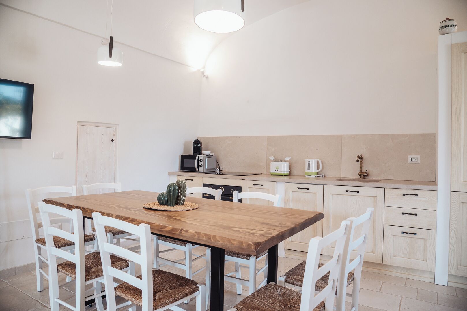 Eine moderne Küche mit weißen Schränken, einem Holztisch und weißen Stühlen.