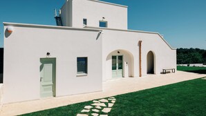 A modern building with a flat roof, a green door, and a paved walkway leading to an entrance. - DIMORA STUNE (Ostuni)