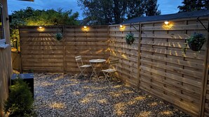 A wooden fence with hanging planters and a gravel patio with foldable chairs. - The Perk Inn, Cosy & Secluded Garden Lodge (Poole)