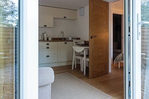 A modern kitchen with white cabinets, a wooden door, and a dining area with a white table and chairs.