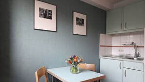 Une cuisine avec une table, des chaises, un vase de fleurs et des tableaux encadrés au mur.