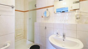 Une salle de bain avec un lavabo, un miroir et une douche.