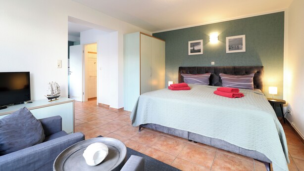 Une chambre d’hôtel avec un lit, une télévision, un canapé et une petite table.