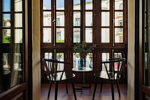 A room with a large window, two chairs, a small table, and a vase with plants. - Suite Balcón Magdalena: Private Terrace, Pool & Wi-Fi in Seville (Sevilla)