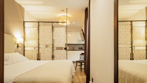 A hotel room with two beds, a desk, and a mirror. - Cathedral Apartment: Historic Center, Giralda & Pool in Seville (Sevilla)