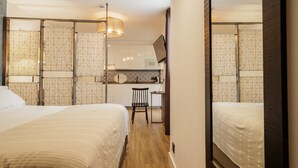 Quarto de hotel com duas camas, uma escrivaninha e uma cozinha compacta.