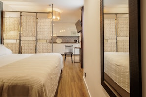 Ein Hotelzimmer mit zwei Betten, einem Schreibtisch und einer Küchenzeile.