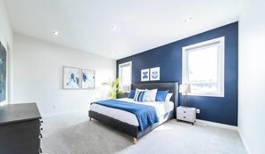 Een slaapkamer met een bed, nachtkastjes en kunstwerken aan de wanden.