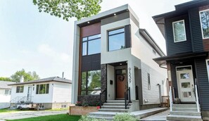 A modern two-story house with a front porch, a garage, and a well-maintained lawn. - Jasper Retreat - AC - Patio - BBQ & Firepit - Near DT/WEM (Edmonton)