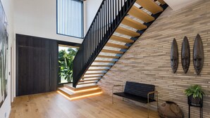 Un intérieur moderne avec un escalier en bois, un banc et un mur orné de trois masques.