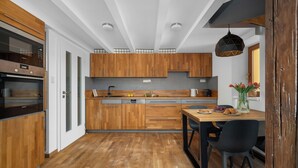 Eine moderne Küche mit Holzausstattung, einem eingebauten Ofen und einem Essbereich mit Tisch und Stühlen.