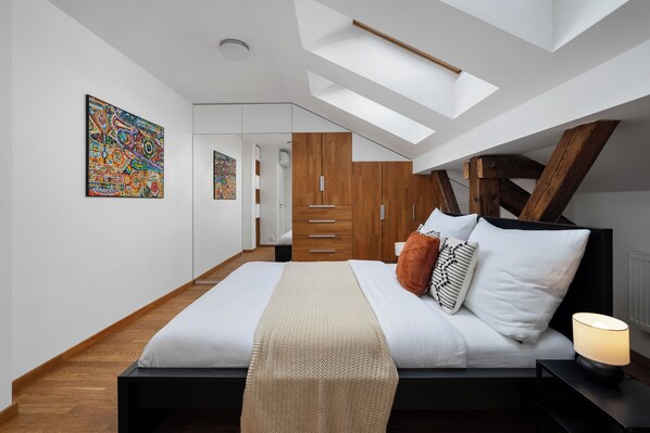 A modern bedroom with a skylight, wooden wardrobe, and a bed with pillows.