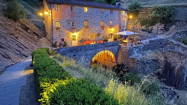 Un bâtiment en pierre doté de nombreuses fenêtres et un pont de pierre qui y mène.
