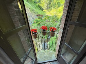 A balcony with a view of a lush garden, a brick wall, and a metal railing. - Valentina apartment, at il Mulino Torrigiani (Capannori)