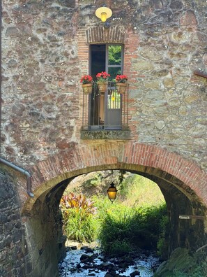 A stone bridge with a window above it, a hanging lantern, and a small stream below. - Valentina apartment, at il Mulino Torrigiani (Capannori)