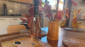 A dining table with a bottle, a vase with dried leaves, and a packaged food item.