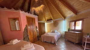 A bedroom with two beds, a wooden ceiling, a stone wall, and a window.