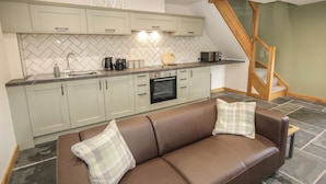 A kitchen with a herringbone tile backsplash, a built-in oven, and a microwave.